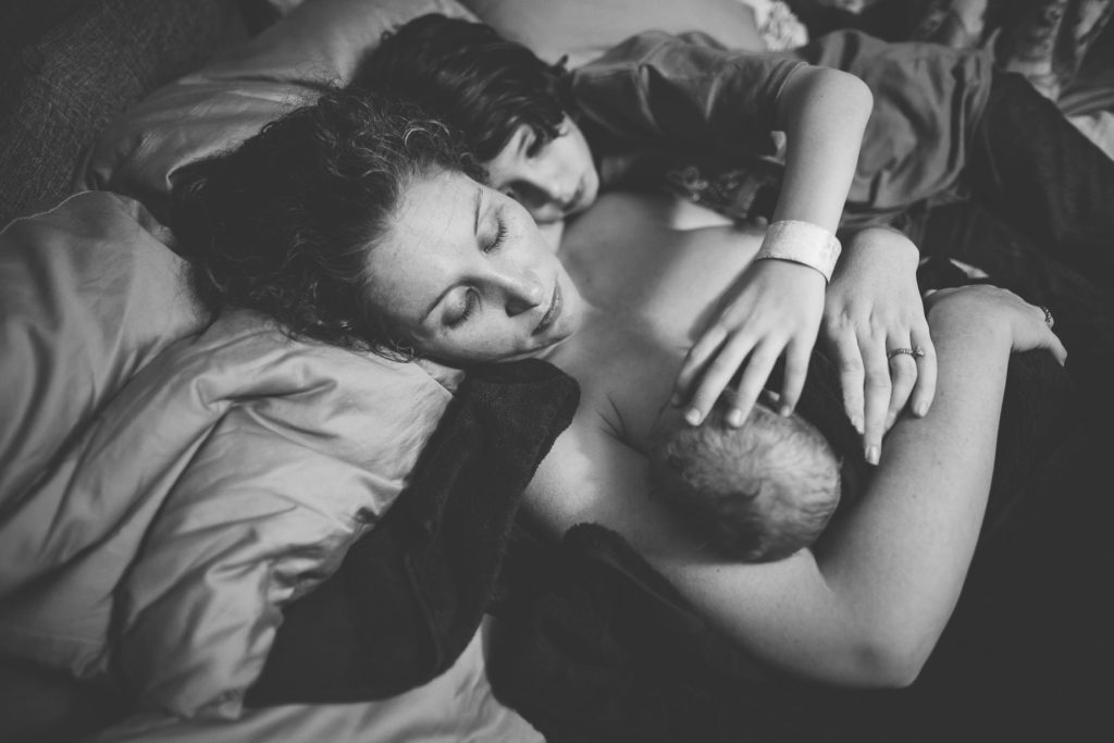 mom and snuggling new baby after home birth Albany NY