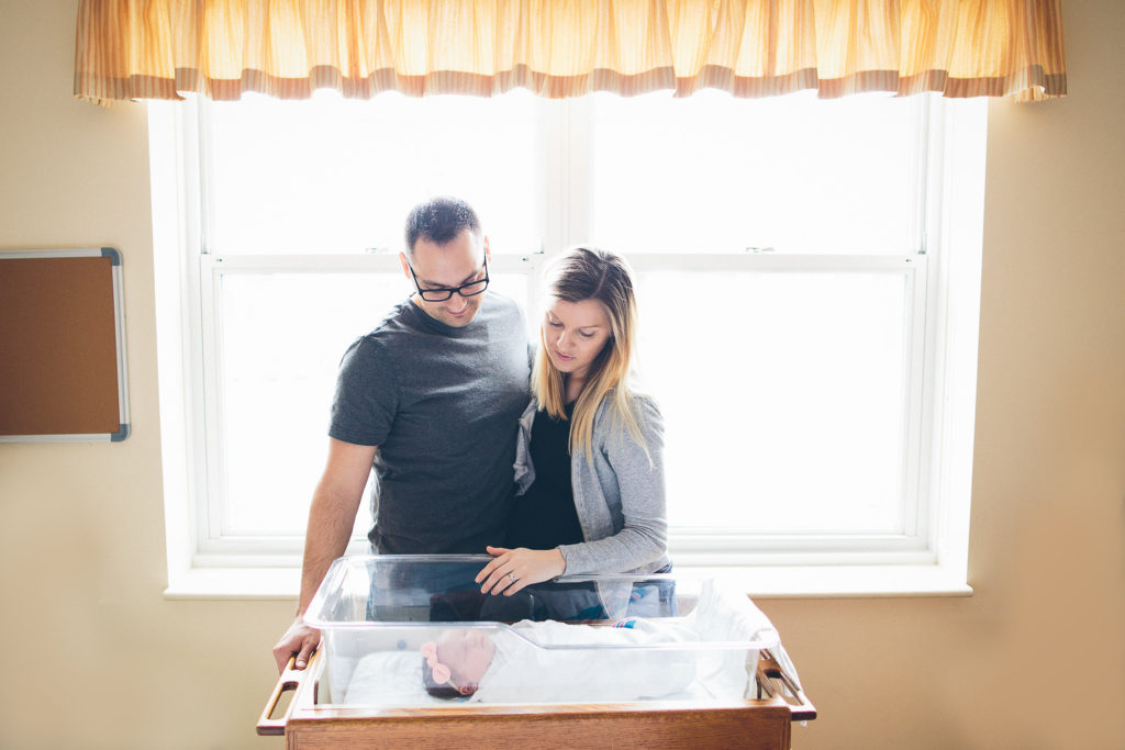 mom and dad stand in front of hospital window Fresh 48 session Albany NY