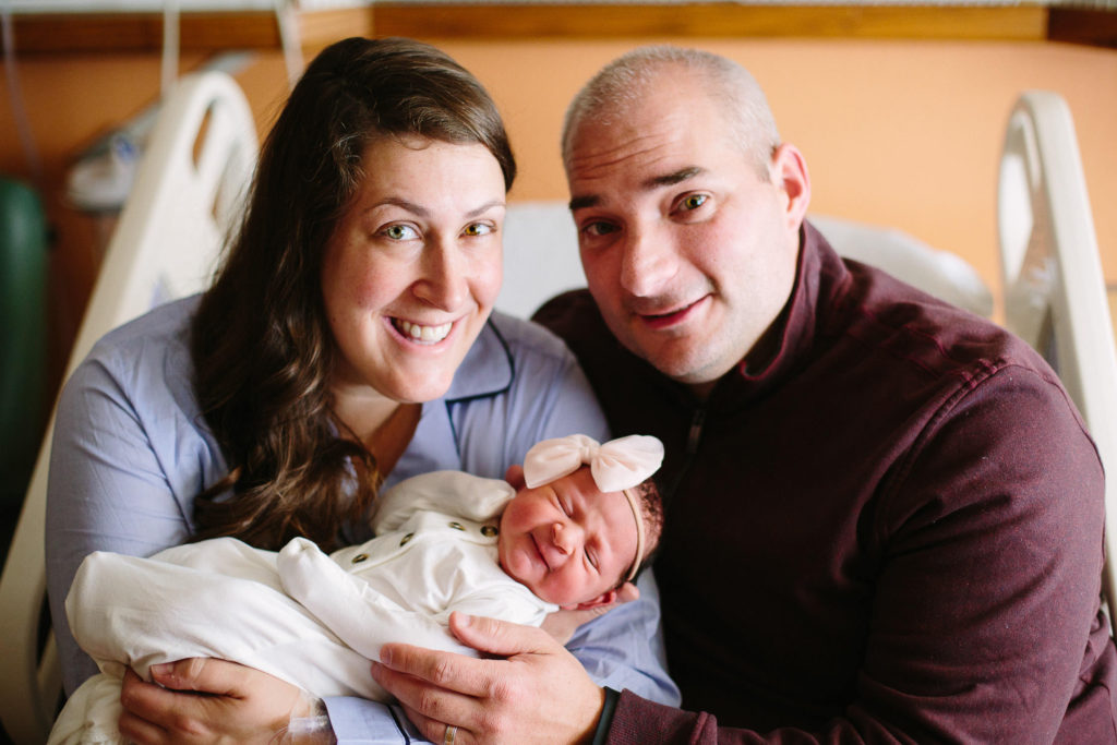 mom and dad holding baby girl on hospital bed fresh 48 session Saratoga NY