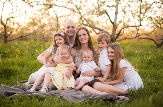 Family picture in apple orchard three little girls and two boys with parents