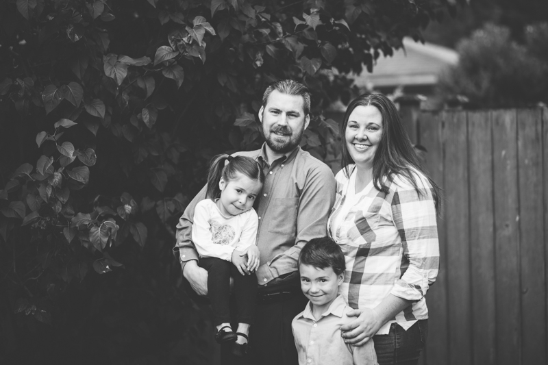 black and white picture of family by a fence and bush