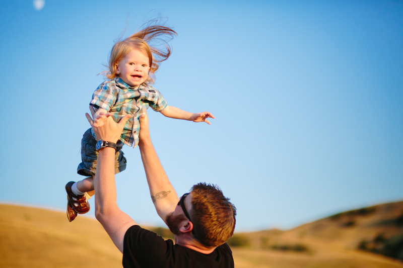 Dad throwing little boy with long hair