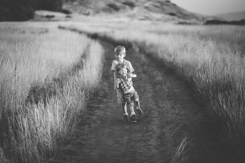 Little boy carrying his baby brother struggling