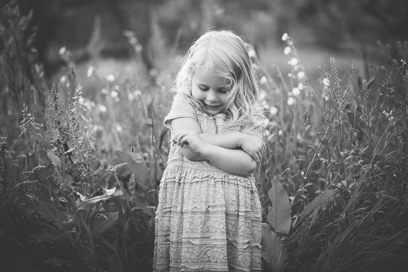 picture of a girl folding her arms looking at a flower