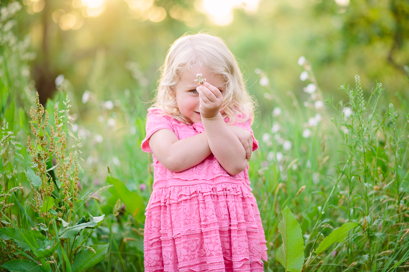 little girl holding up a small flower
