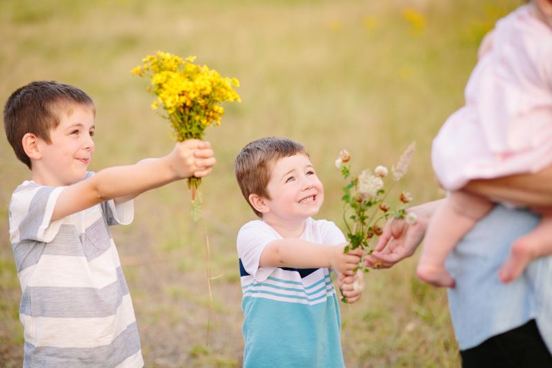 two little boys giving flowers to their mom
