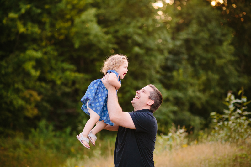 dad holding baby girl as an airplane