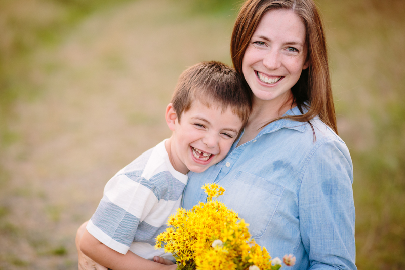 son hugging mom and holding yellow flowers