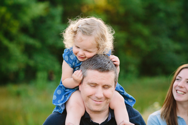 Little girl sitting on dads neck, hugging head