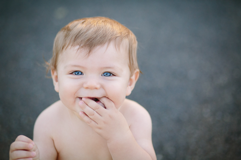 Blue eyed baby looking up fingers in mouth