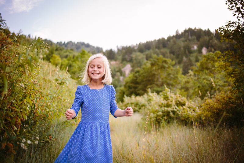 young girl in blue dress running down a mountain