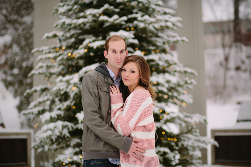 young couple standing infant of lit tree