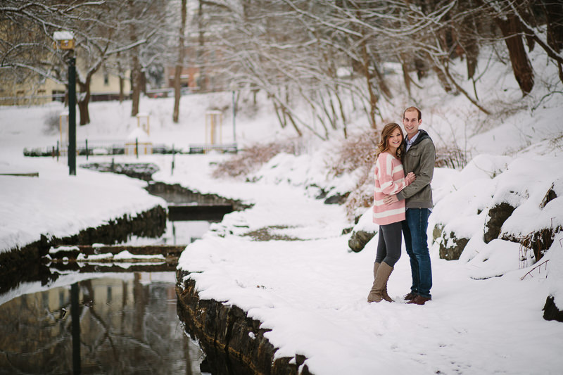 young couple standing in snow near stream