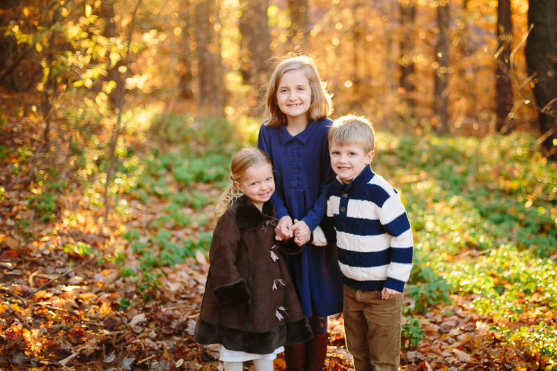 three kids standing together leaves on ground