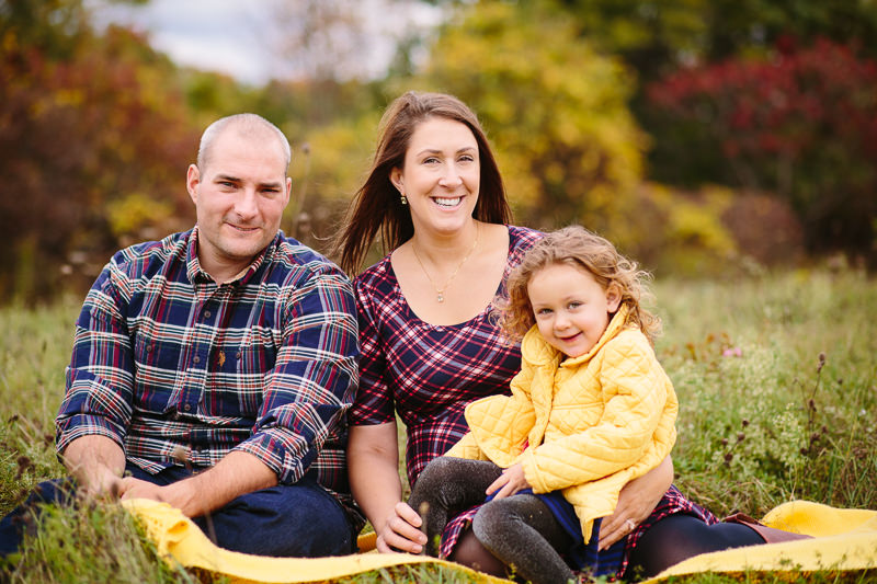 mom and dad wearing plaid girl in yellow jacket