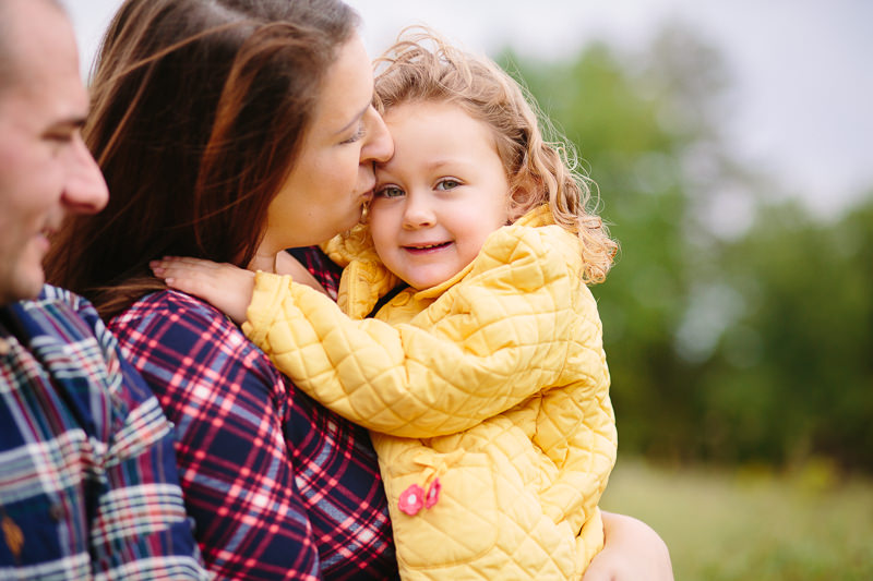 mom kissing little girl on forehead 