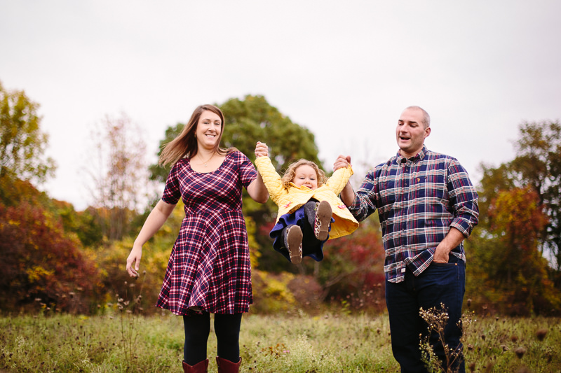mom and dad swing girl in yellow jacket