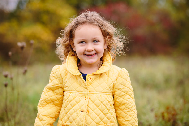 close up of curly haired little girl in yellow jacket