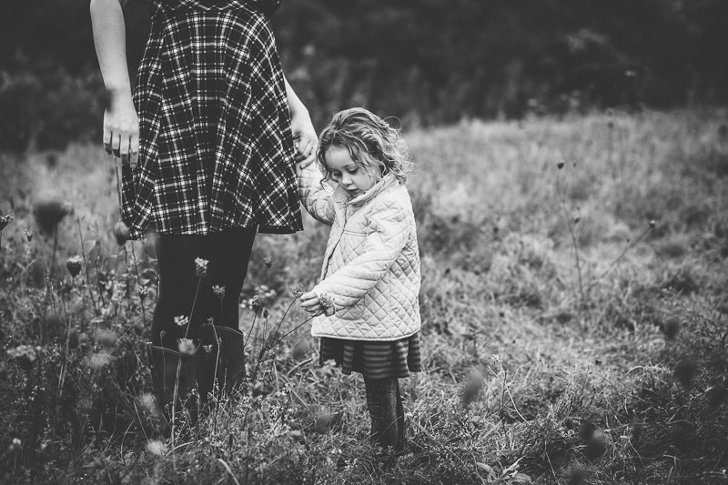 girl holding mom's hand looking at flowers