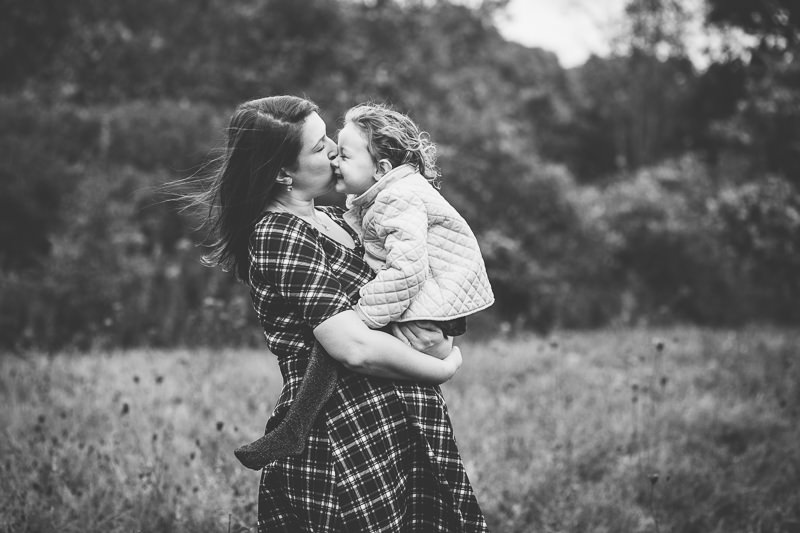 mom kissing daughter in a field