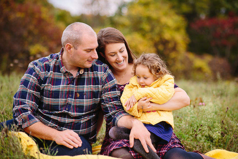 family sitting in a field on yellow blanket