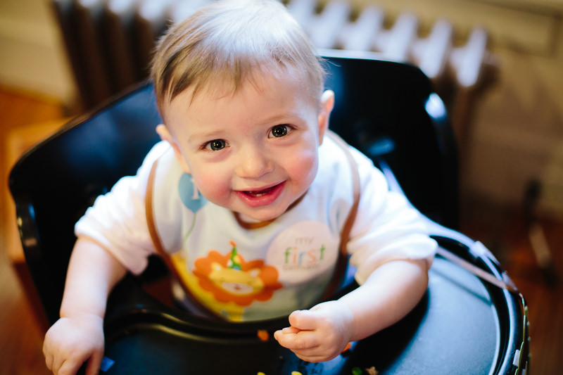 baby boy sitting in high chair wearing birthday bib