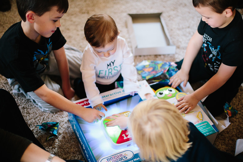 birthday boy sitting with cousins looking at new toy