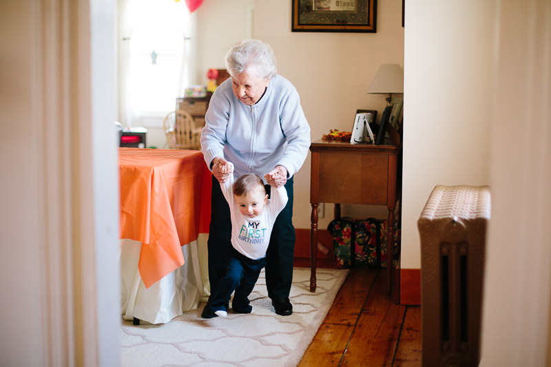 grandma helping her grandson walk in a house