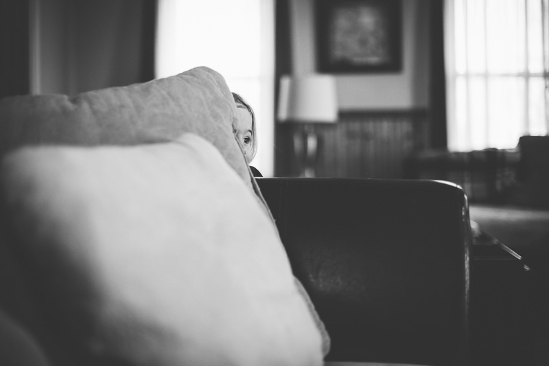 young child peeking behind pillows