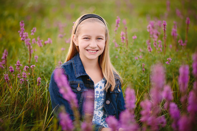 blonde girl sitting in a field of purple flowers 
