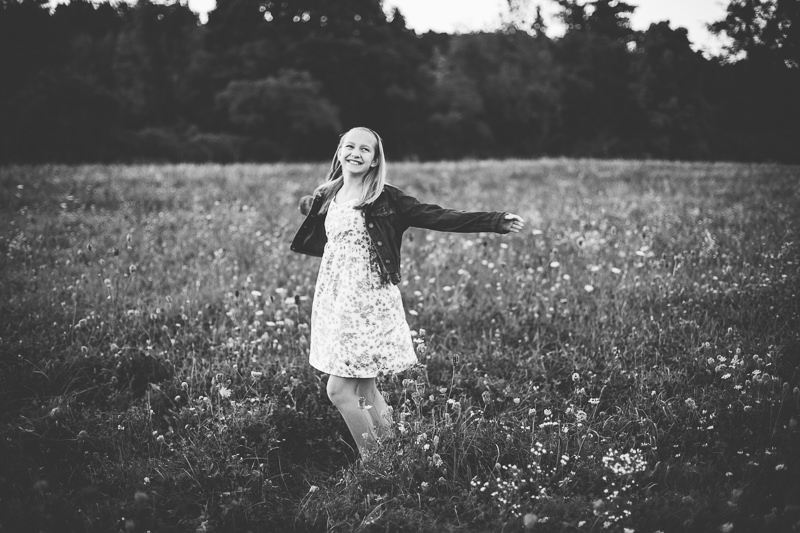 girl in flower dress spinning in a field 
