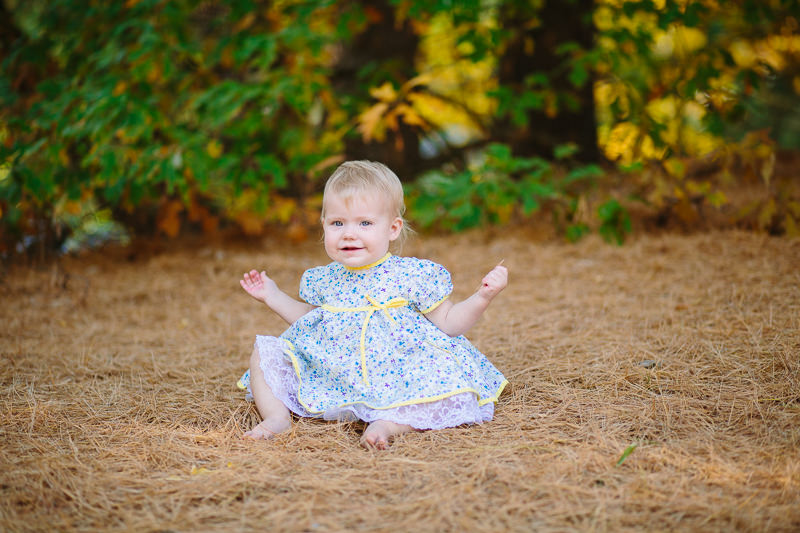 baby girl sitting in soft pine needles