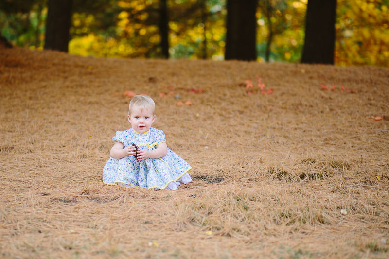 baby girl playing in soft pine needles