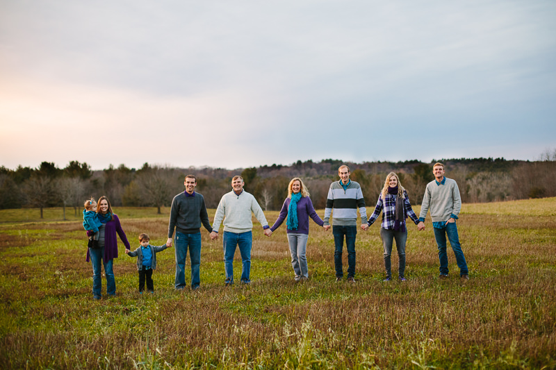 extended family holding hands in field 