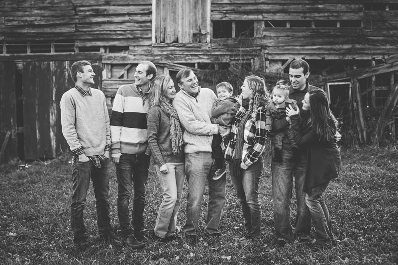 family laughing together in front of old barn
