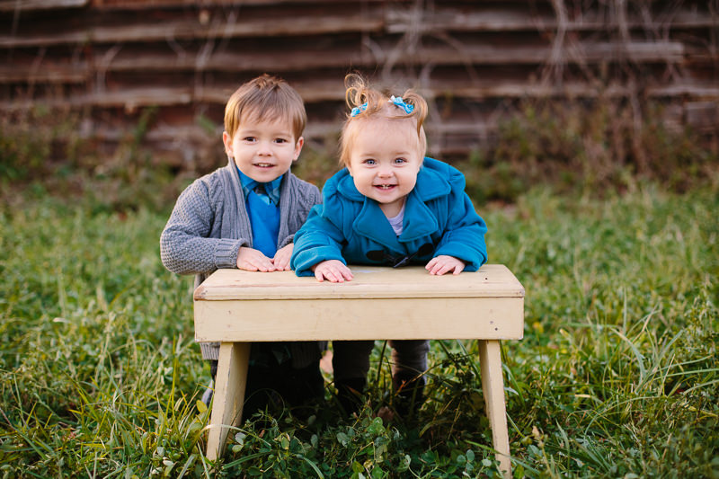 brother and baby sister leaning on stool