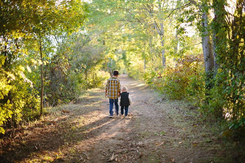 boy walking with baby brother down a trail