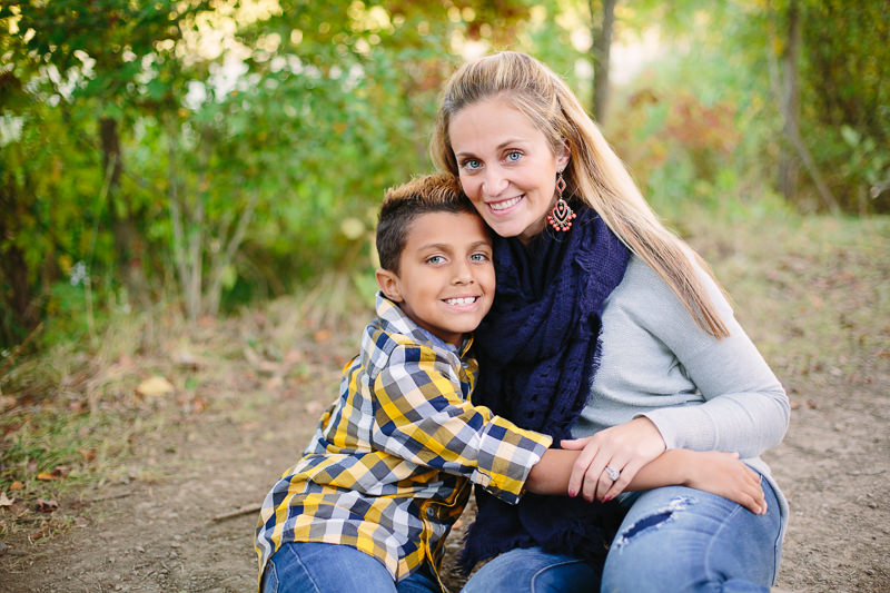 mom snuggling with her son sitting on ground
