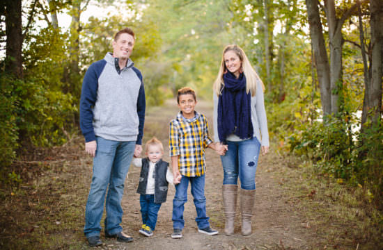 mom dad and two sons holding hands on trail