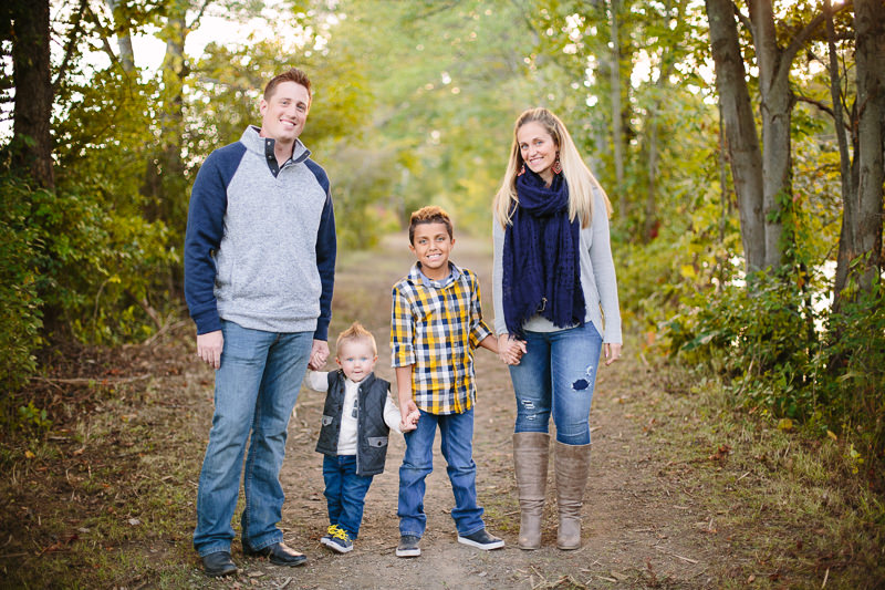 mom dad and two sons holding hands on trail