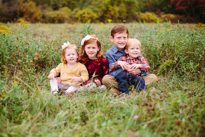 four red head children sitting in field