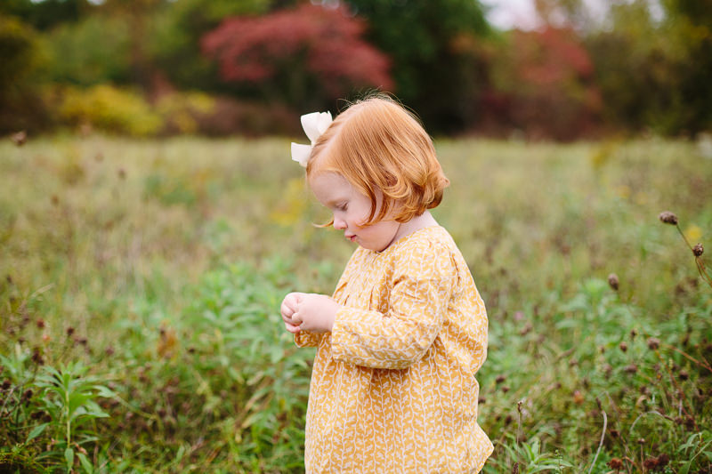 toddler girl looking at a flower