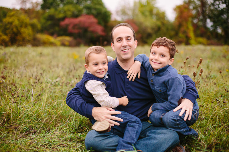 dad holding his sons in a field