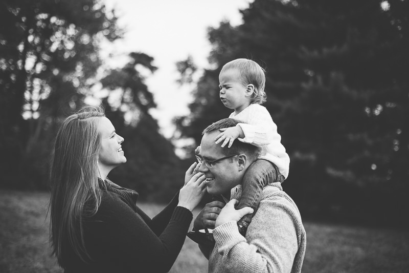 sad baby on dads shoulders mom helping