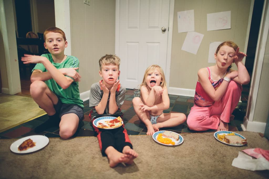 four kids eating dinner on the floor