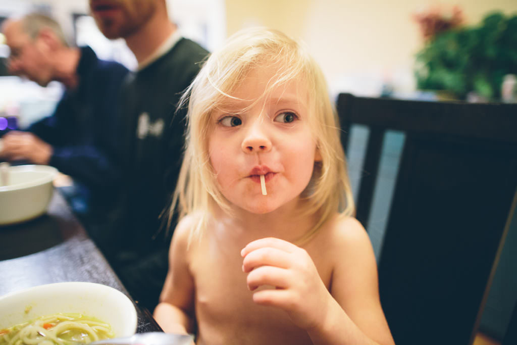 young girl eating a noodle