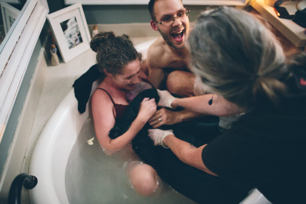 dad excited in tub after birth of baby boy