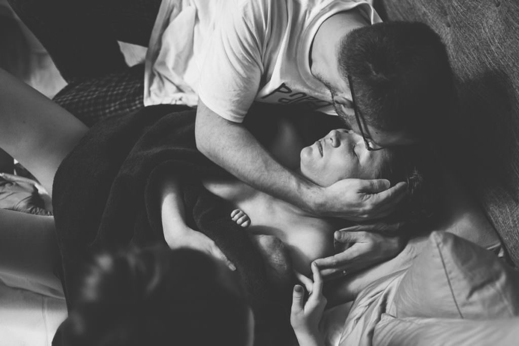 husband kissing wife after labor