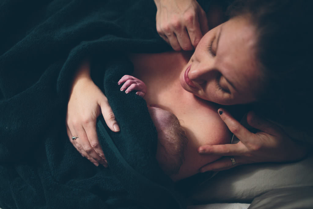holding new baby on chest wrapped in blanket