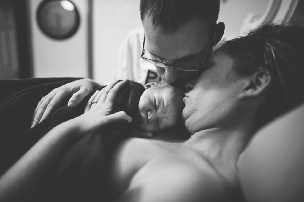 mom and dad kissing new baby after home birth